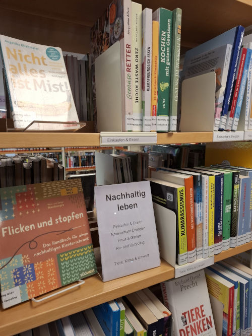 Zu sehen ist ein Regal, auf dem verschiedene Bücher mit Titeln wie »Nicht alles ist Mist!« oder »Flicken und stopfen« stehen.