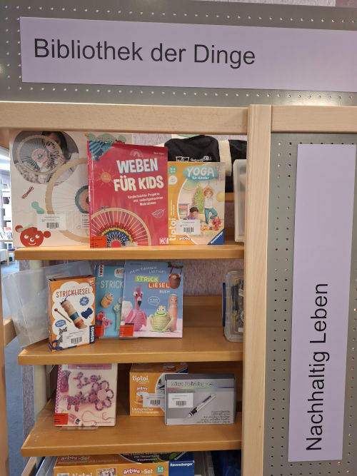 Zu sehen ist ein Regal, in dem verschiedene Gegenstände, die zum Verleih angeboten werden, ausgestellt sind, z.B. eine Strickliesel, ein Lautsprecher oder ein Polierstift